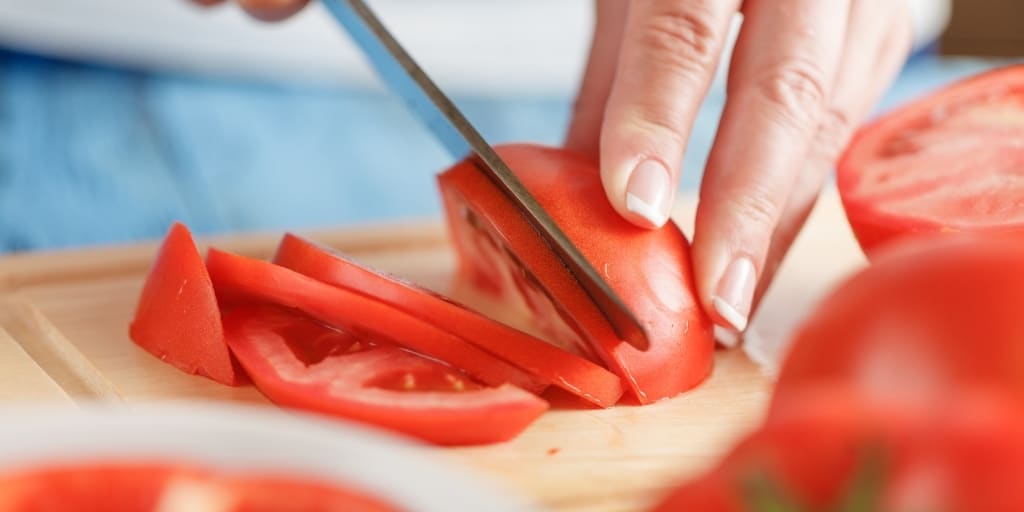 best tomato knife slicing through a red tomato on a cutting board