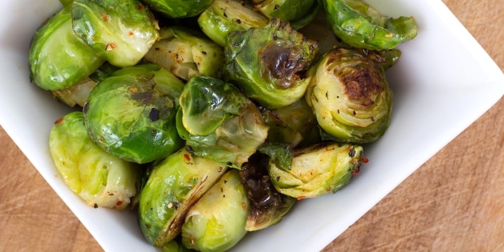 Brussel Sprouts in a white square bowl on table top ready to be served with chicken and dumplings