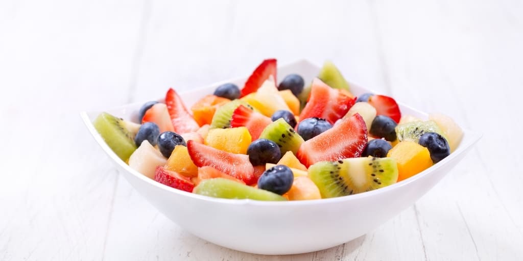 fresh mixed fruit in a bowl on a white table to be served with chicken and dumplings